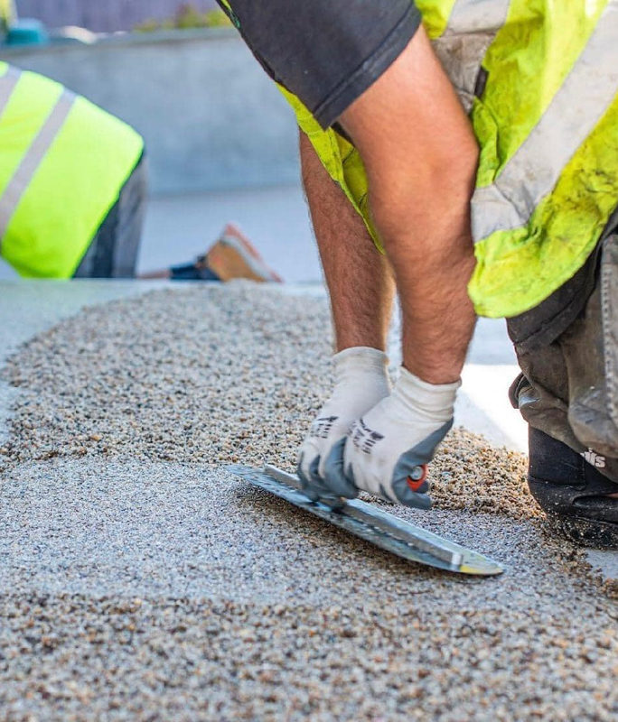 A worker smoothing a resin bound surface.